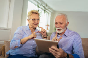 Smiling deaf senior couple talking using sign language on the digital tablet's cam